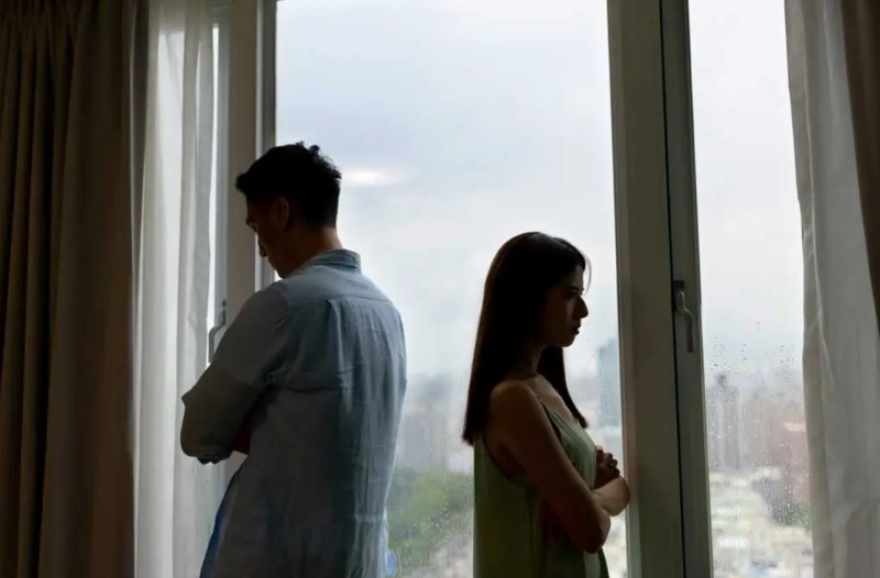 Hình bóng của một cặp vợ chồng châu Á quay lưng vào nhau trước cửa sổ ở nhà