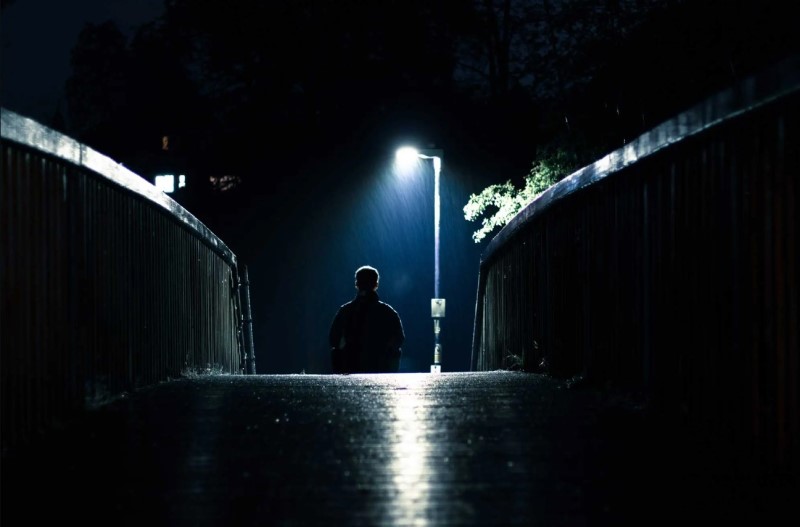 ảnh chụp người đàn ông ngồi dưới cơn mưa đêm